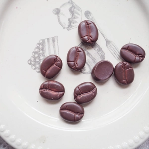 Realistic 15mm dark brown resin coffee beans scattered on a white ceramic plate