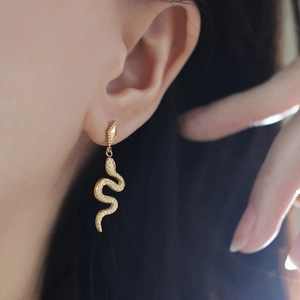 Detail of 18K gold plated snake-shaped earrings with scale texture and rhombus stud