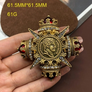 Detailed close-up of a vintage bronze cross brooch with red gems and crystal accents