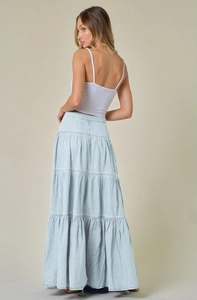Vista posteriore di una gonna lunga in denim azzurro a balze con design a strati su modella