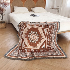 Bohemian geometric woven cotton blanket with fringe tassels on white bed in home setting