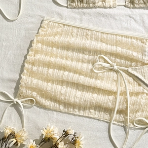 Detail eines cremefarbenen Bikini-Tops mit 3D-Blumenspitze und Schnürung Details