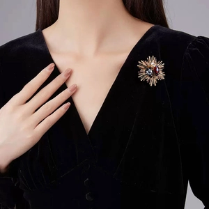 Luxury gold starburst sunflower brooch with colorful gemstones on a black velvet dress