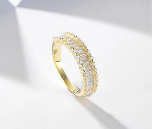 Macro shot of gold baguette and round-cut cubic zirconia stones on the half-eternity ring