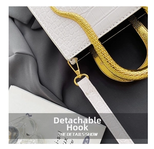 Detail of the white crocodile-patterned leather bag featuring a gold detachable hook