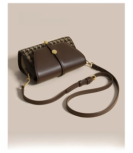 Detailed close-up of brown leather and houndstooth fabric stitching on cross body bag