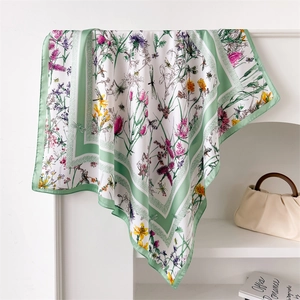Détail d'un foulard en soie avec motifs de fleurs sauvages et bordure verte élégante