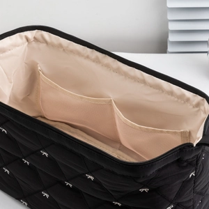 Interior detail of quilted hair dryer bag with dual mesh compartments and beige lining
