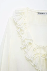 Detail showing ruffle V-neckline and tie design on cream chiffon blouse for women