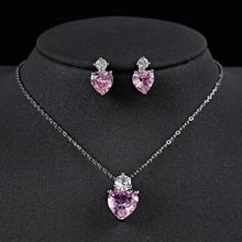 Detailed view of silver necklace and earrings set featuring pink heart-shaped gemstones