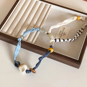 Dettaglio della collana con ciondolo a cuore vintage con tessuto blu e perline legno