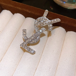 Detailed close-up of a silver brooch with inlaid crystals on a soft beige jewelry box