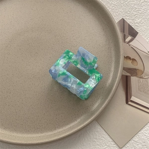 Dettaglio di un fermaglio per capelli quadrato in acetato con texture marmorea blu