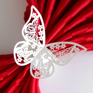 Elegant white laser-cut butterfly paper napkin ring holder on a red napkin for table decor