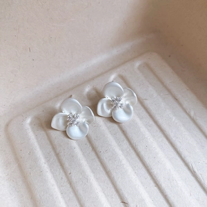 Detail of white flower stud earrings with matte petals and sparkling zircon centers