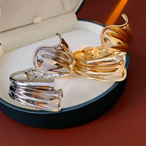 Irregular twisted metal cuff bracelet in gold and silver finish on luxury gift box