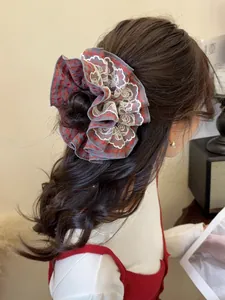 Detail view of a large red plaid scrunchie with lace trim worn on wavy hair for a vintage look