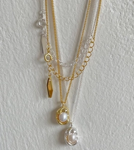 Detail view of gold and silver pearl pea pendants on delicate link chains for women