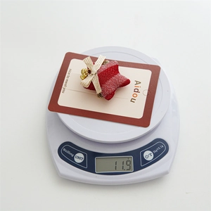 Close-up of red star hair clip with bells and gold bow on weight scale for Christmas