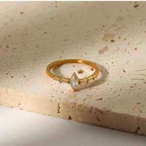 Macro shot of gold-plated ring with marquise-cut zircon set on a travertine stone
