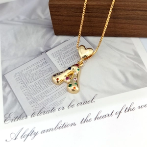 Macro shot of gold letter A pendant with colorful stones and heart bail on wood