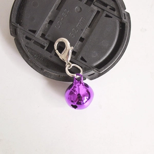 Macro shot of a purple metal bell pendant with a silver lobster clasp on a black cap