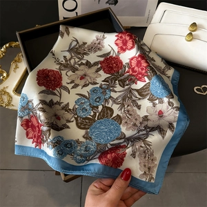 Close-up of square floral silk scarf with vibrant peony patterns and elegant blue edges