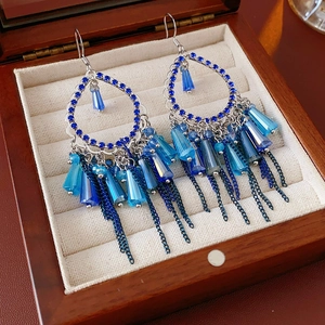 Dettaglio di orecchini bohémien con cristalli blu, perline a goccia e nappe in metallo