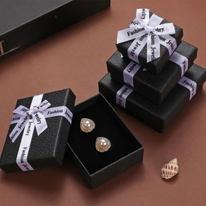 Detail of elegant pearl drop earrings in a premium black jewelry box with white ribbons