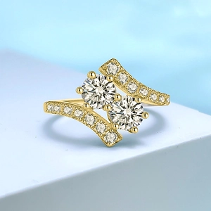 Elegante anillo dorado con dos piedras principales y banda ondulada con pavé