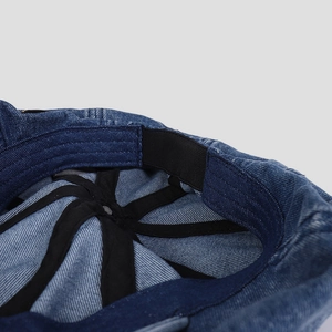 Detailed macro view of the inner adjustable elastic band inside the denim newsboy cap