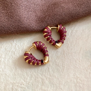Détail de créoles coeur en or 18k avec texture de soie bordeaux tressée