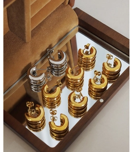 Detailed close-up of gold and silver chunky C-shaped hoop earrings in a walnut jewelry box