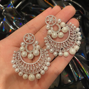Detailed shot of silver chandelier earrings with white pearls and sparkling zircons