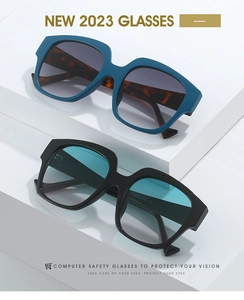 Detail view of large frame sunglasses with blue and black frames on a white pedestal