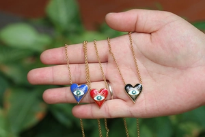 Detail of colorful enamel heart pendants with evil eye pattern on golden chains