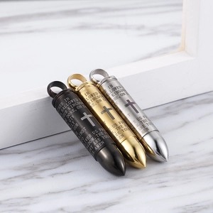 Three cross bullet pendants in black, gold and silver on white marble surface