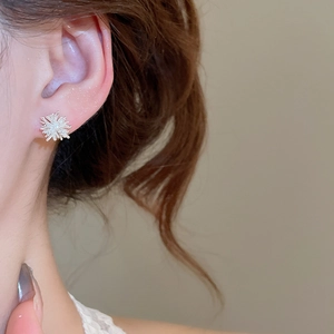 Close-up of elegant silver snowflake earring with zircons worn on a model's ear