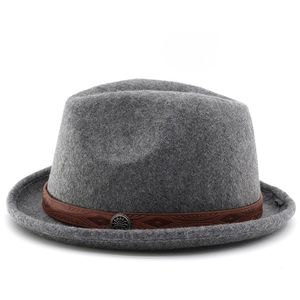 Detail of grey wool jazz hat featuring dark brown printed leather band and silver emblem