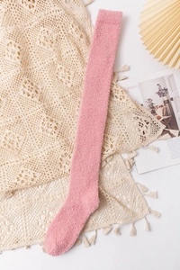 Pink coral fleece over-the-knee sock laid on lace fabric for a cozy winter vibe