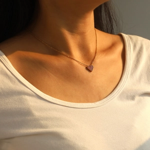 Close-up of heart pendant necklace with gold beaded edge on woman neck