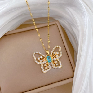 Close-up of golden butterfly pendant with blue rectangle zircon and clear stones