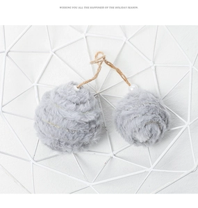 Detail of grey faux fur pom poms with jute rope and white pearls in a metal basket