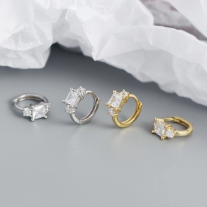 Detailed view of silver and gold hoop earrings with rectangular and round cubic zirconia