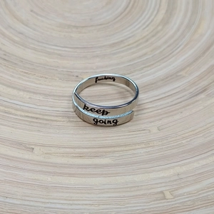 Detail of double-layer stainless steel ring with keep going engraved lettering