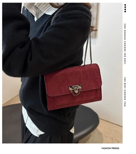 Détail du sac bandoulière bordeaux en daim avec fermoir géométrique et bandoulière chaîne