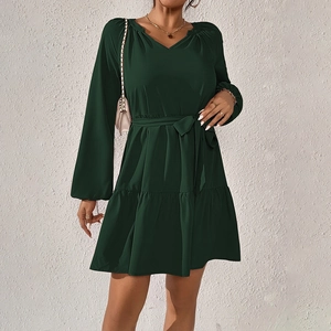 Dettaglio dell'abito verde scuro con scollo a V, maniche lunghe e cintura in vita