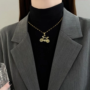 Luxurious gold bicycle pendant necklace with sparkling crystals worn by a model