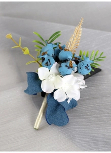 Macro detail of groom boutonniere with white flowers, blue berries and golden accents