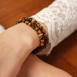 Close-up of tiger eye stone cylinder bracelets with gold accents on a model wrist